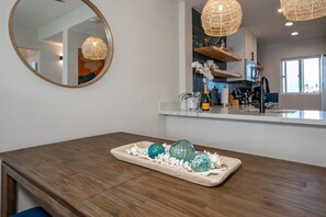 A modern kitchen with a wooden countertop, a round mirror, and decorative glassware. - Upscale Oceanfront Penthouse Vistas (Kihei)