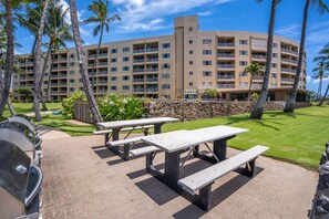 A hotel with multiple floors, outdoor picnic tables, and a barbecue area. - Upscale Oceanfront Penthouse Vistas (Kihei)