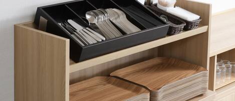 A wooden drawer unit with compartments for utensils and glasses.