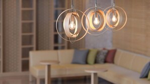 A modern interior with a wooden dining table, a sofa with colorful cushions, and a unique circular pendant light fixture. - HOTEL MYSTAYS Atsugi (Atsugi)