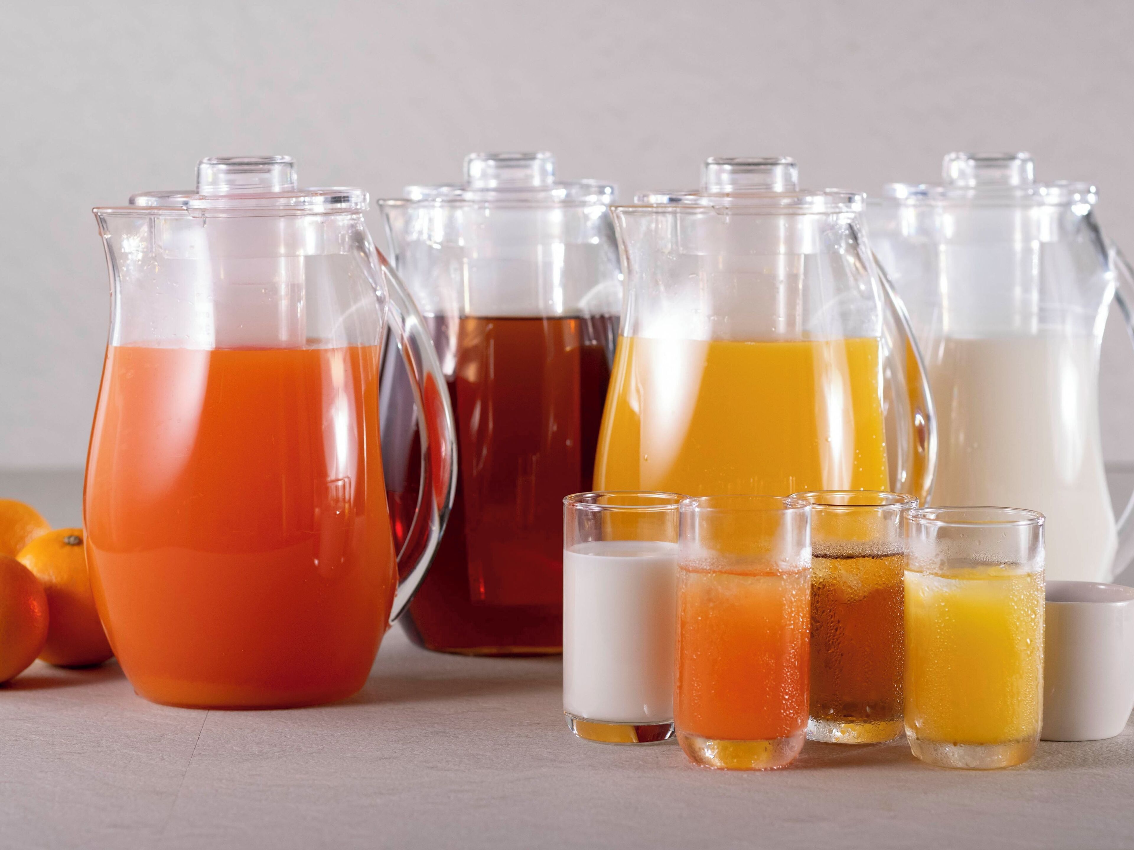 Varios recipientes de vidrio con líquidos de diferentes colores, probablemente zumos o bebidas, y algunos vasos vacíos.