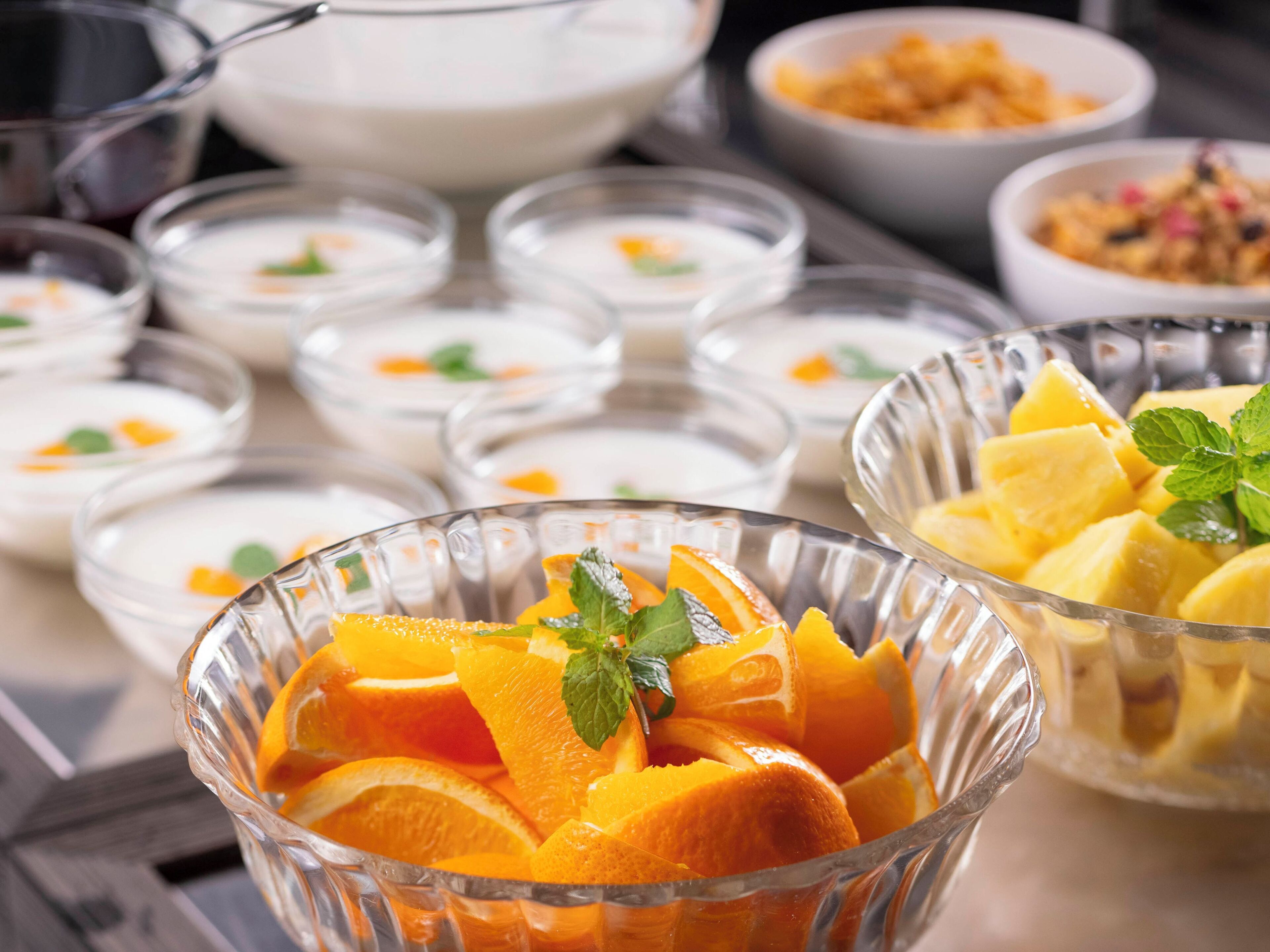 Diverse pietanze, tra cui ciotole di frutta e yogurt, disposte su un tavolo.