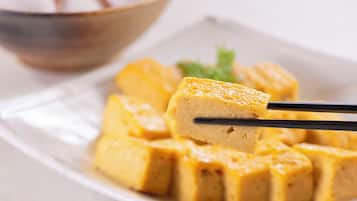 Une assiette de cubes de tofu, avec des baguettes servant à en prendre un.