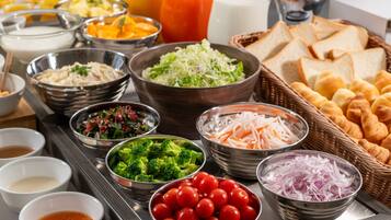 A buffet spread with various food items including salads, fruits, and bread.