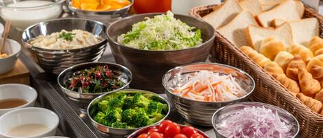 A buffet spread with various food items including salads, fruits, and bread.