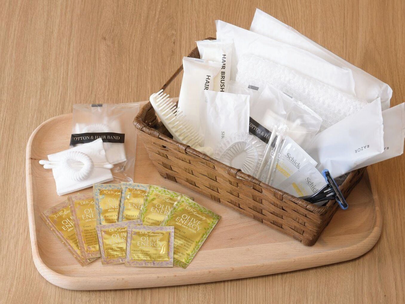 A wooden tray with a hairbrush, cotton & hair band, and several packets of olive energy facial cream.