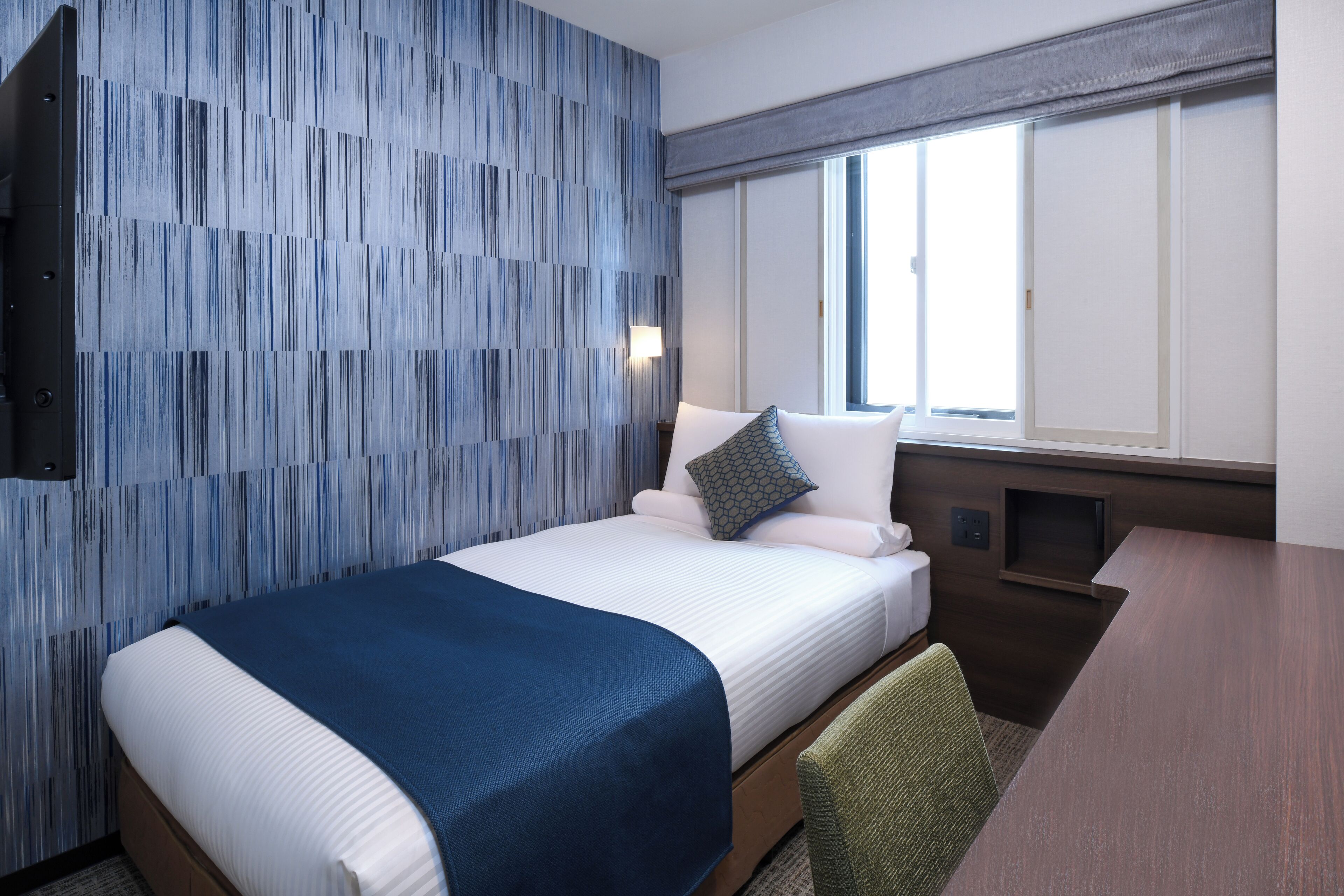 Una habitación de hotel con cama, escritorio y ventana.