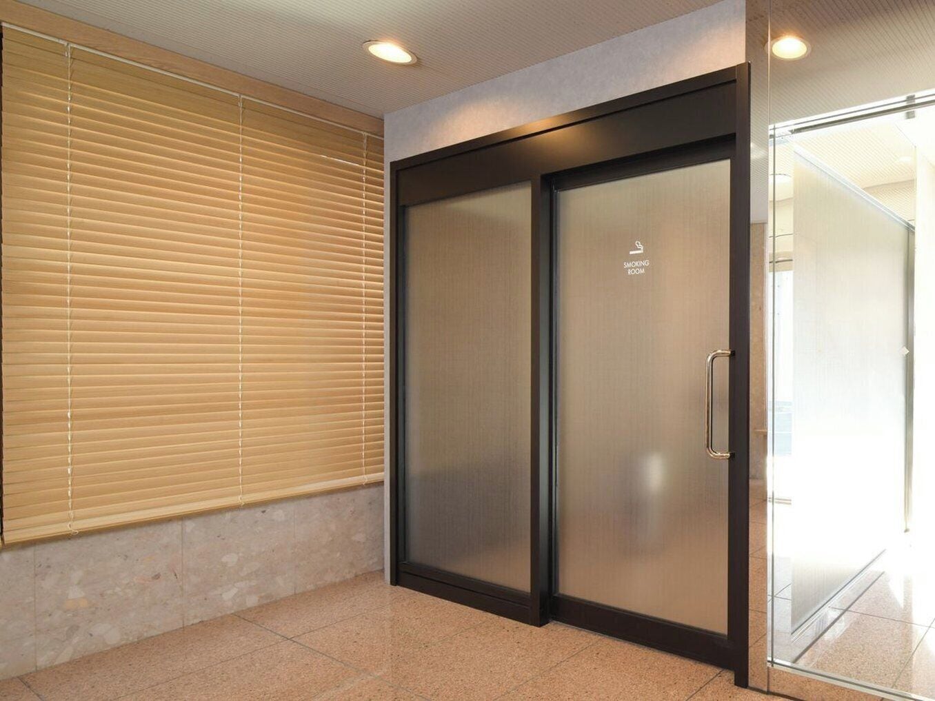 A modern elevator with a glass door and a sign indicating a smoking room.