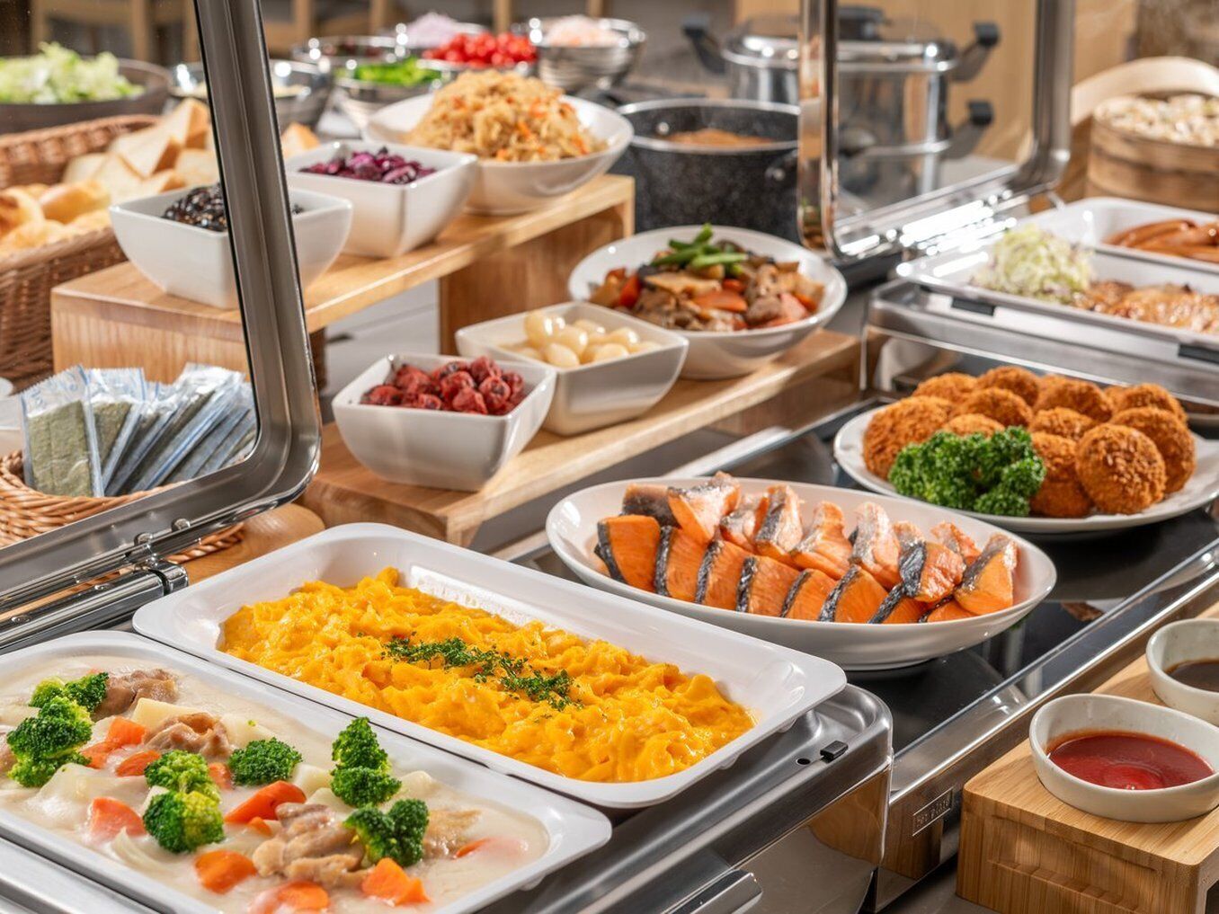 A buffet with various dishes including salmon, mashed potatoes, and a variety of salads.