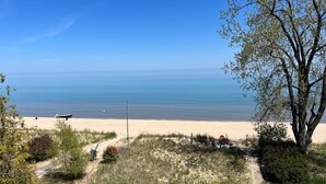 Una playa con vista despejada al océano, un sendero arenoso y algo de vegetación.