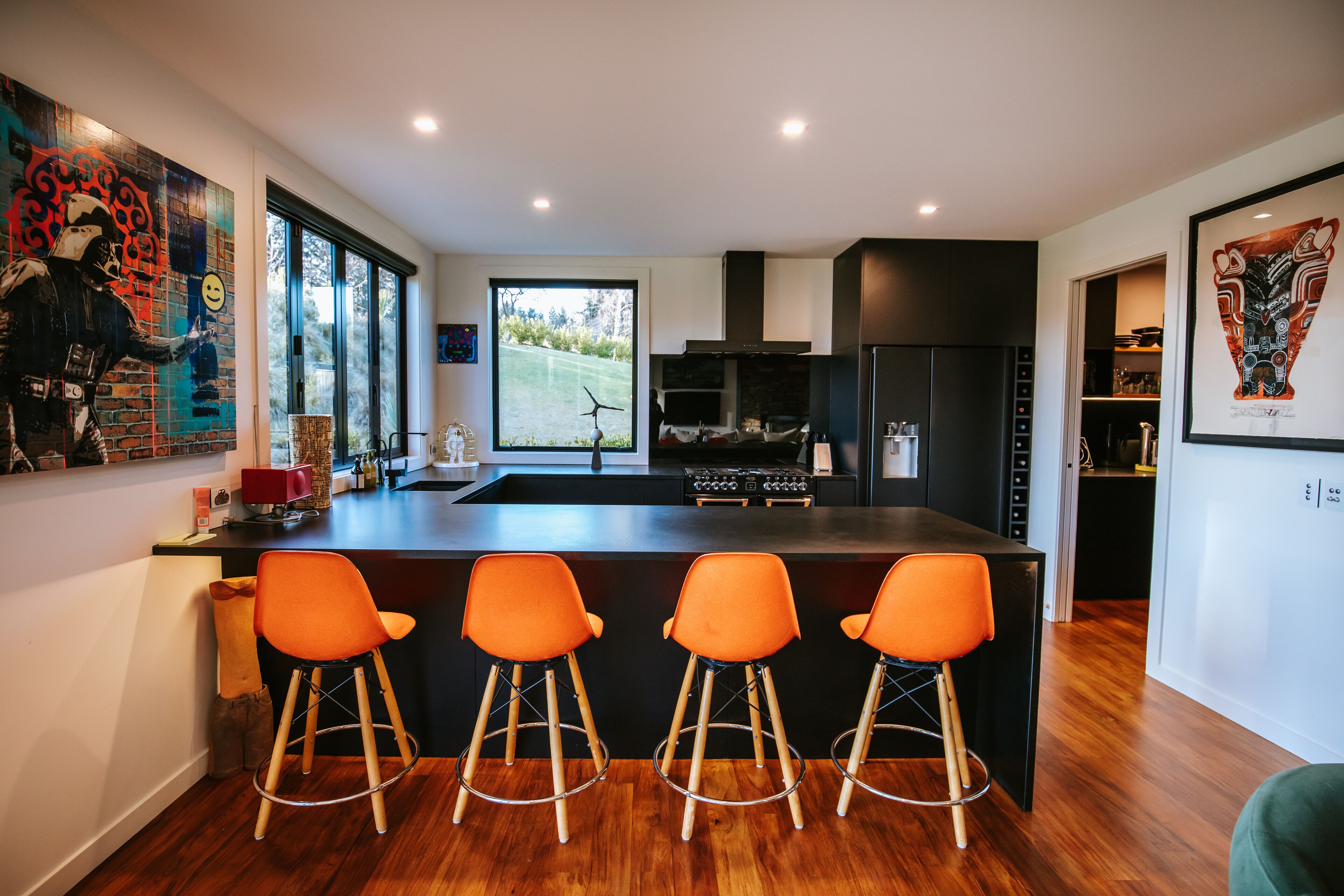 A modern kitchen with a central island, bar stools, and a large window.