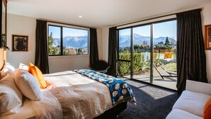 Un dormitorio con cama, una silla, un ventanal con vistas a la montaña y una puerta corrediza de vidrio que da a un espacio al aire libre.