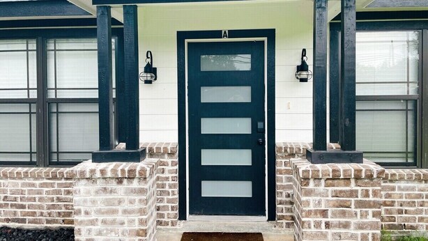 A house with a dark blue door, white brick walls, and a small porch with two lantern-style lights. - Charming 2-Bed Apartment in Houston (Houston)