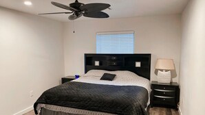 A bedroom with a bed, a nightstand, a lamp, a ceiling fan, and a window with blinds. - Charming 2-Bed Apartment in Houston (Houston)
