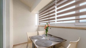 A dining area with a table set for four, surrounded by chairs, and a vase with flowers on the table. - Holiday apartment with air conditioning and Internet (Zambratija)