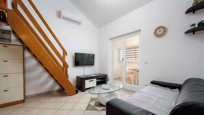 A modern living room with a staircase, a flat-screen TV, a glass coffee table, and a sofa. - Holiday apartment with air conditioning and Internet (Zambratija)
