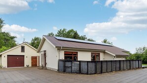 A single-story building with a sloped roof, a garage, and a fenced area.