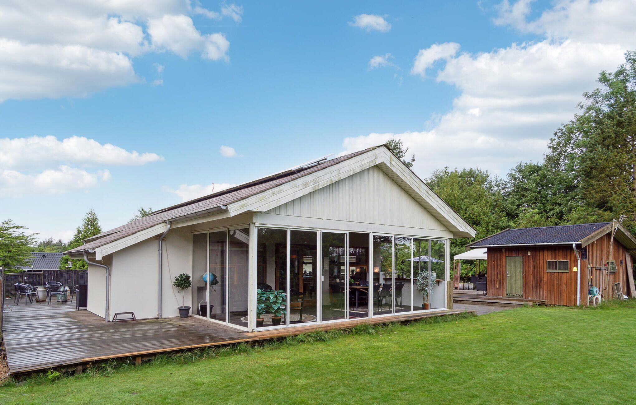A single-story house with a large glass front and a wooden deck.