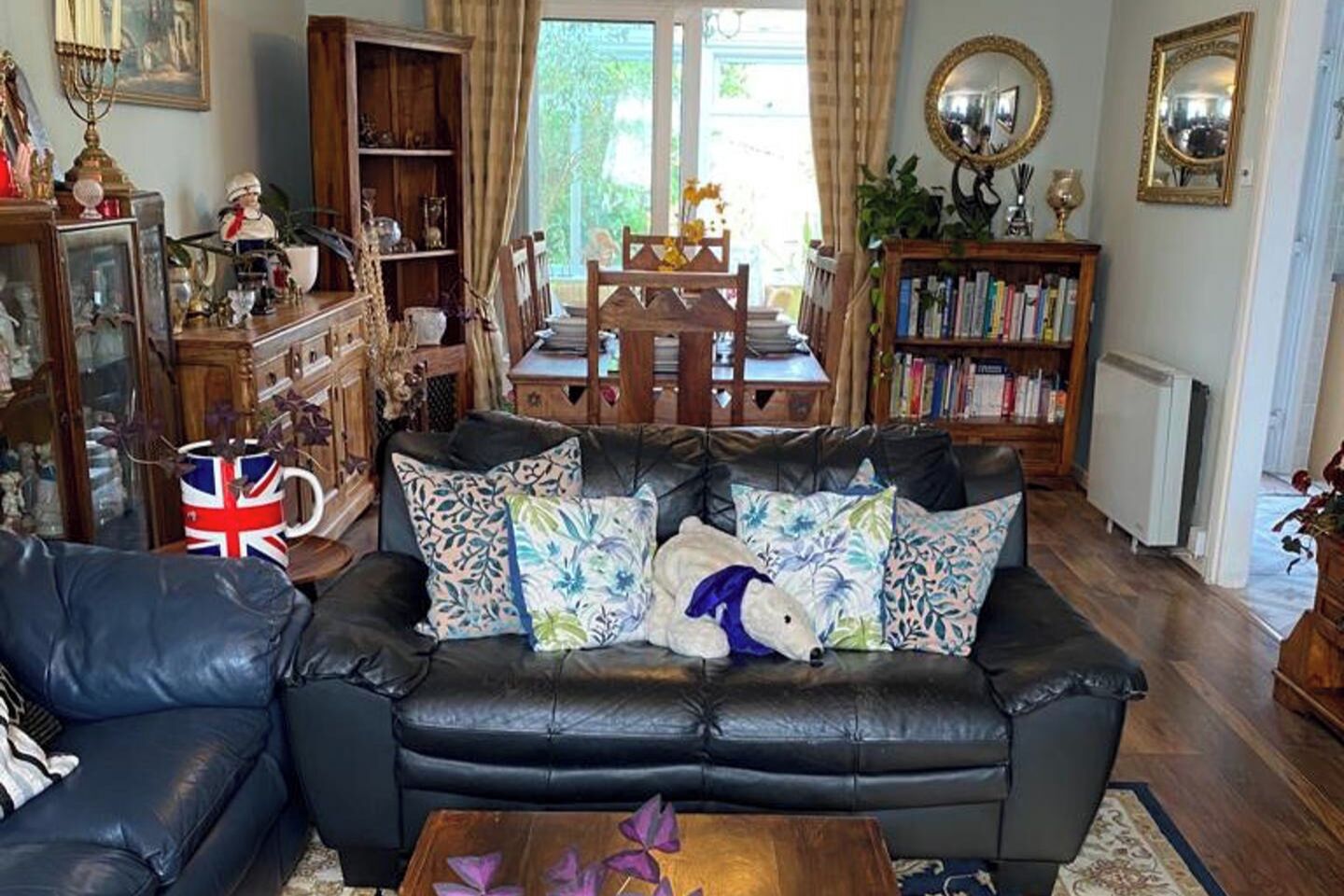 A cozy living room with a leather sofa, a wooden coffee table, and a bookshelf filled with books.