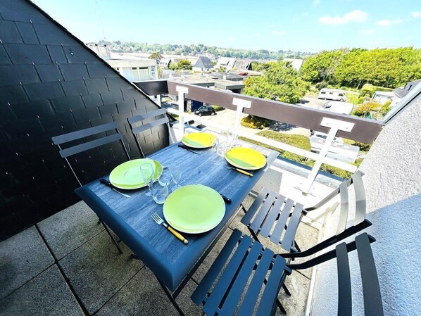 Eine Dachterrasse mit einem Tisch für vier Personen, Stühlen und Blick auf die Stadtlandschaft.
