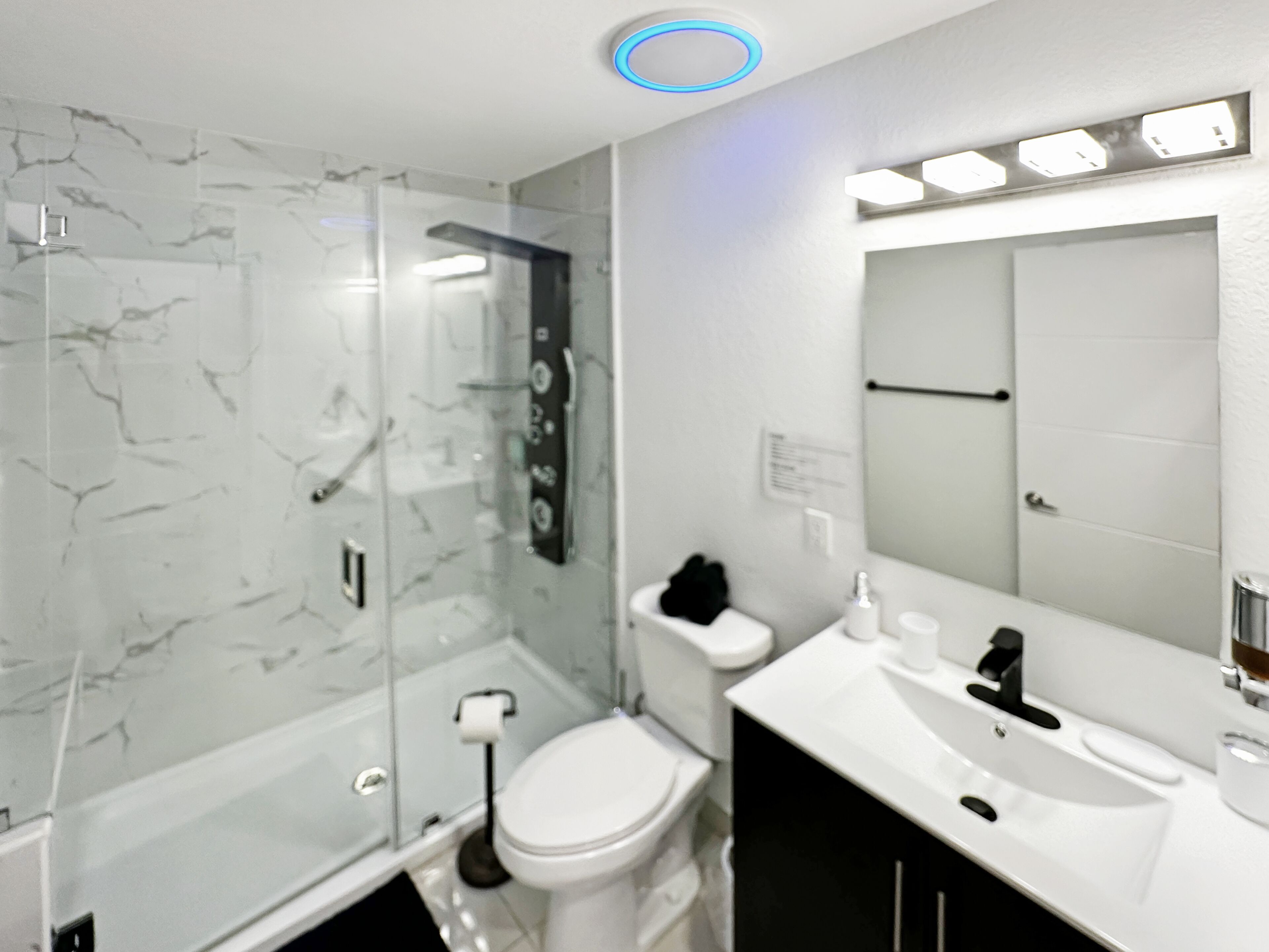 A modern bathroom with a glass-enclosed shower, a white toilet, and a vanity with a mirror.