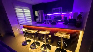 Eine moderne Küche mit Barbereich, inklusive Barhocker und einer Arbeitsplatte mit Geräten.