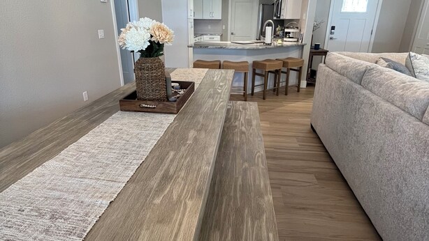 Una sala moderna con una mesa de centro de madera, un sofá y una cocina al fondo.