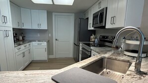 Una cocina moderna con armarios blancos, electrodomésticos de acero inoxidable y encimera de mármol.