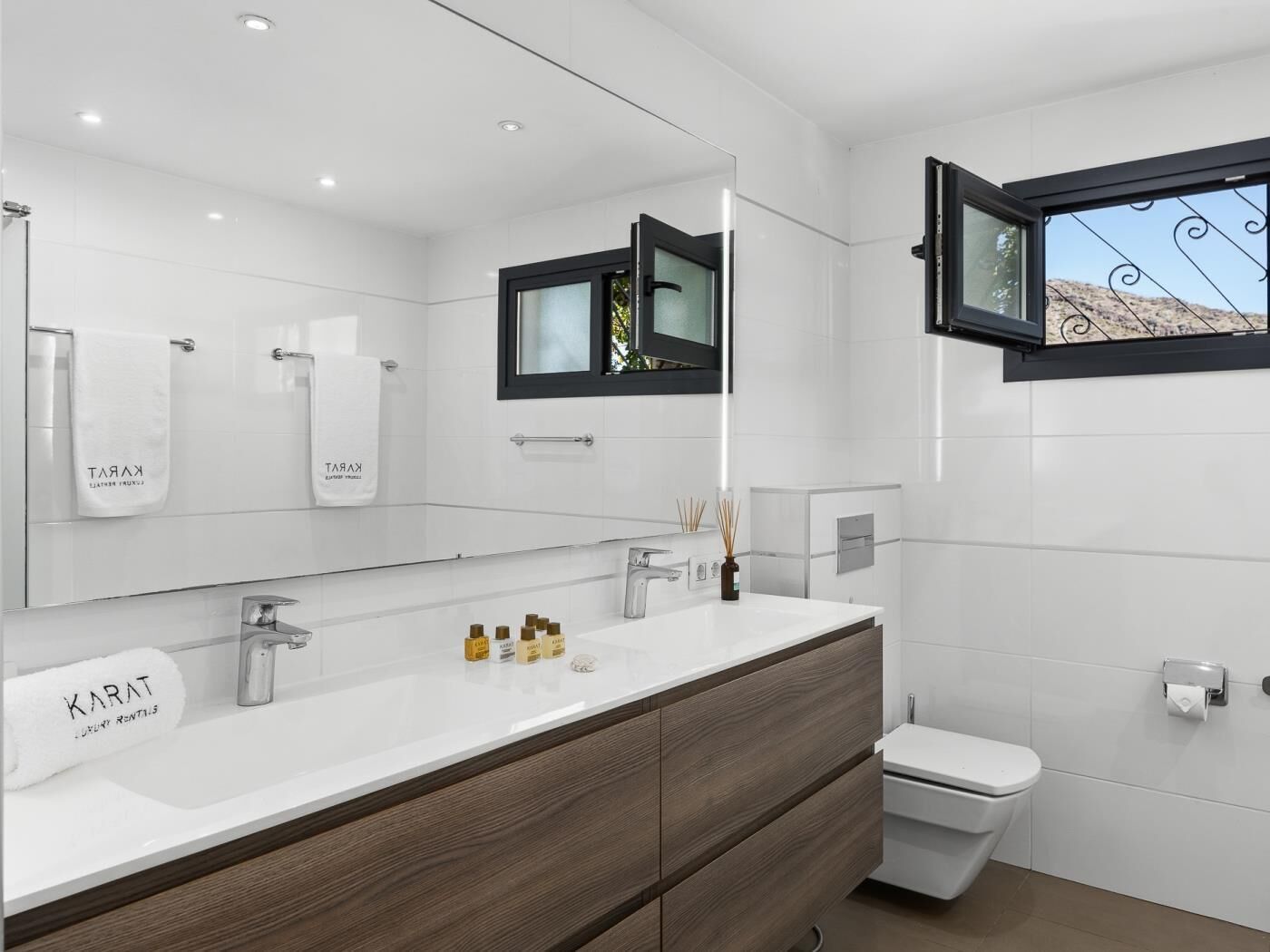 Une salle de bain moderne avec un meuble-lavabo blanc, un miroir et des toilettes.