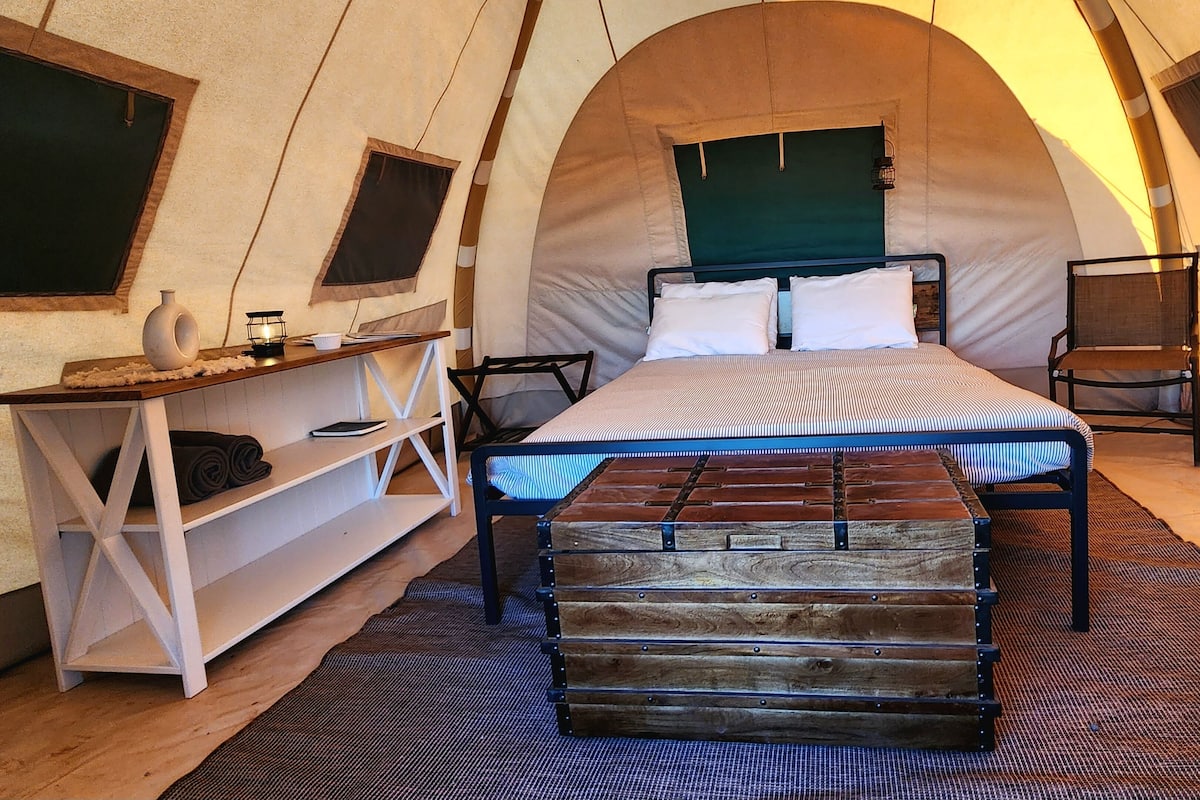A cozy tent-style room with a bed, a small table, and a chair.