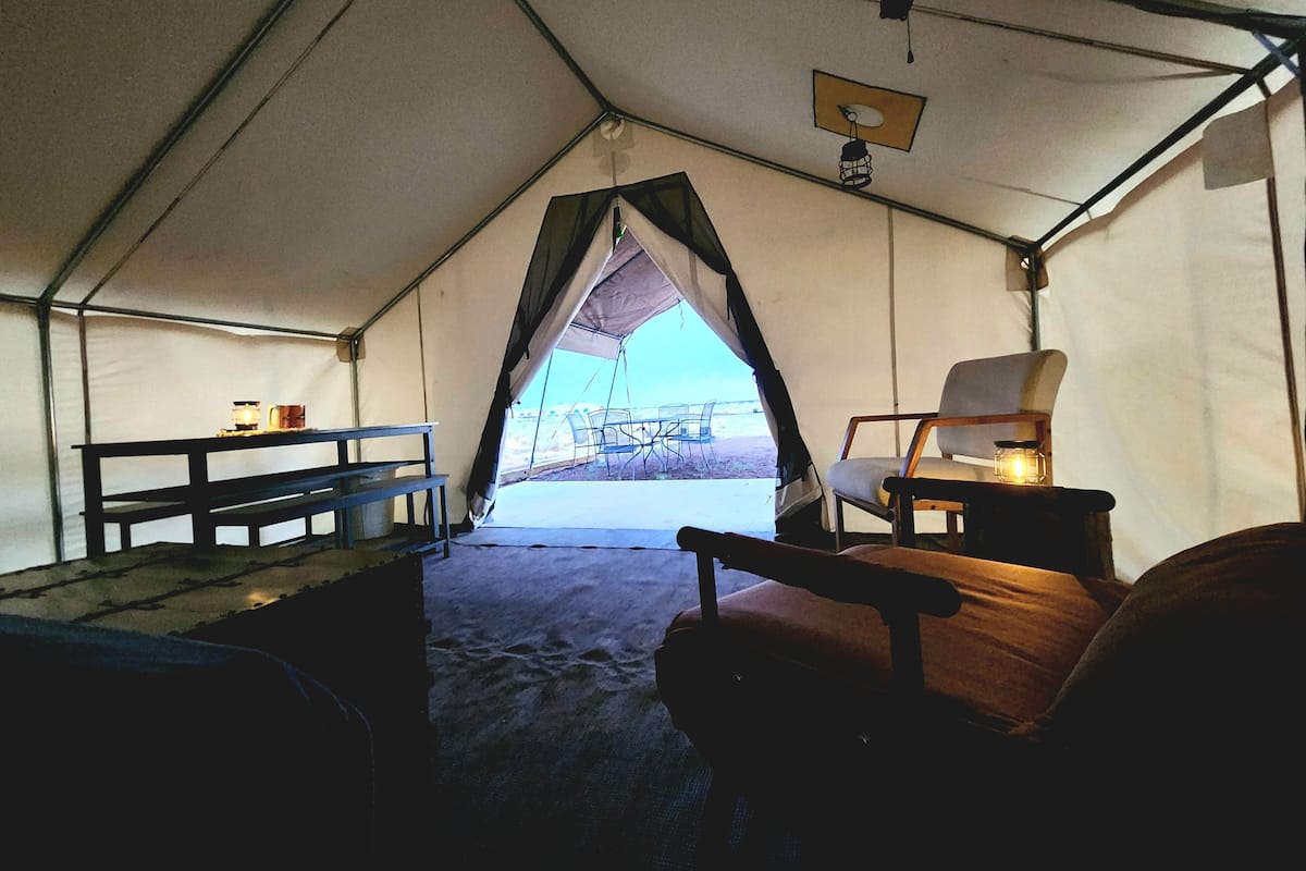 A tent with a bench, a chair, and a table.
