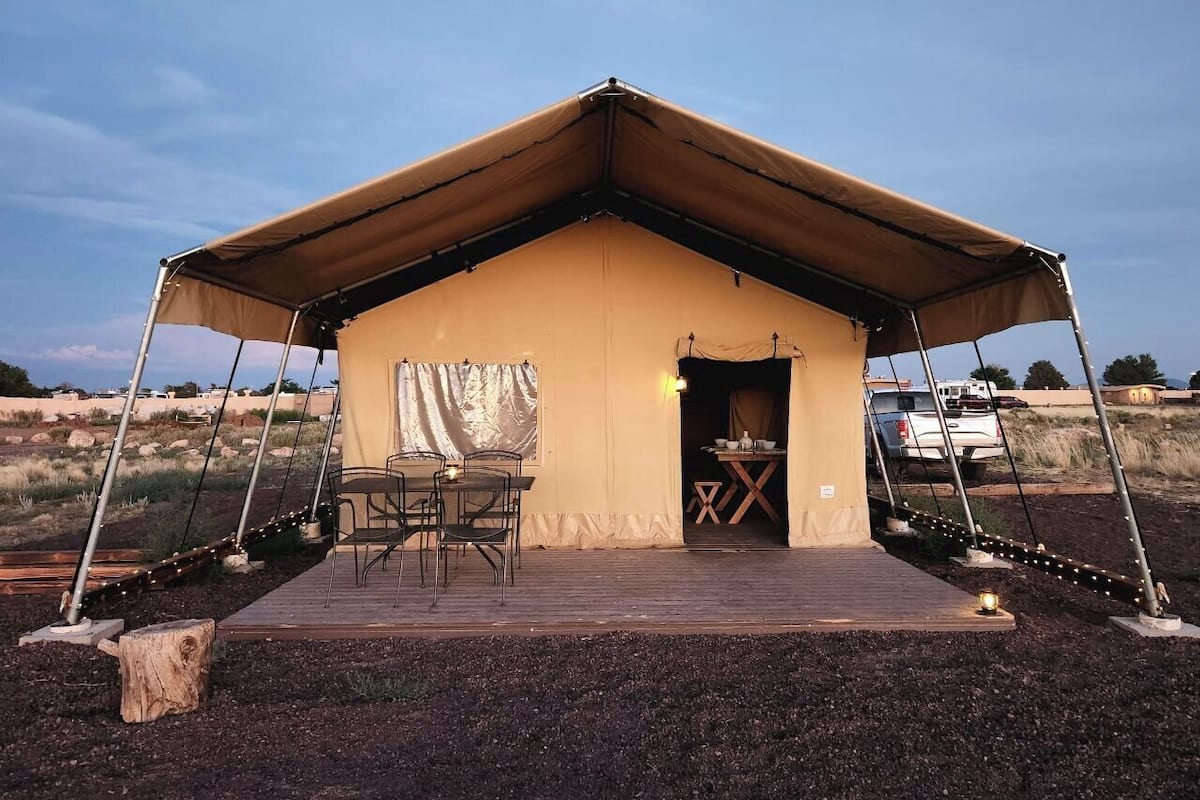 A tent with a wooden deck, a table, and chairs outside.