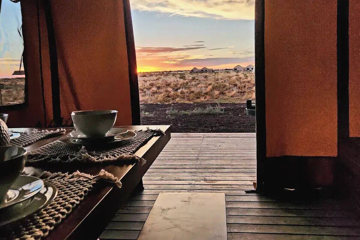 A wooden deck with a view of a desert landscape at sunset.