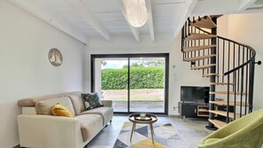 Uma sala de estar moderna com sofá, uma mesinha, televisão e escada em espiral.