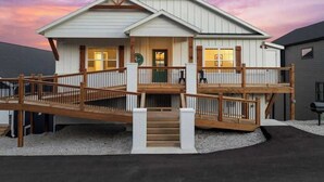 A two-story house with a wooden deck and a covered front porch. - Cozy Lakeview Lodge - Pools, Private Hot Tub & Sauna, Game Room (Branson)