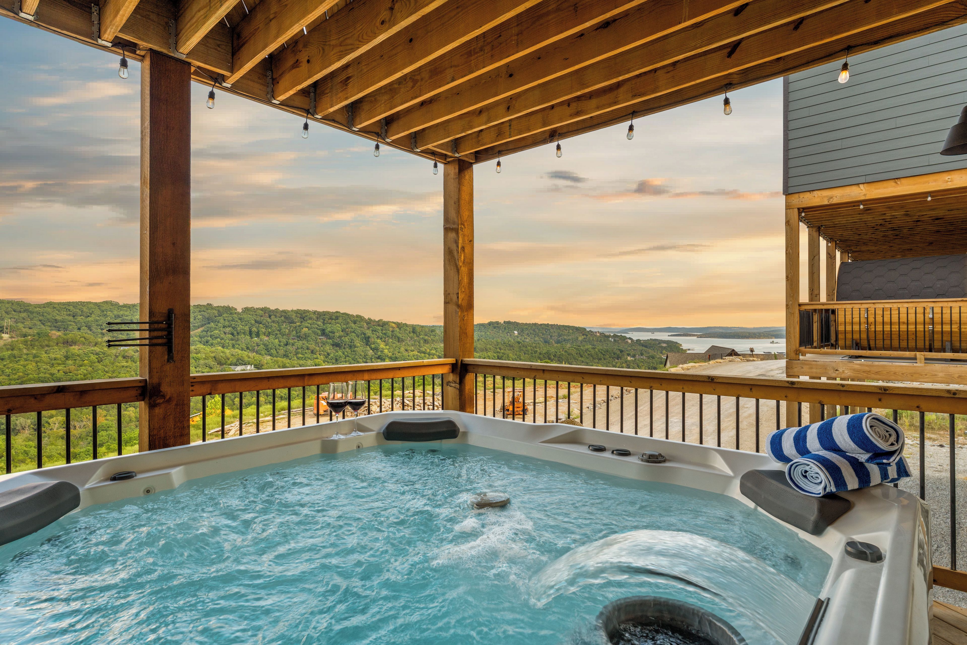 A hot tub on a wooden deck with a view of a forested landscape.
