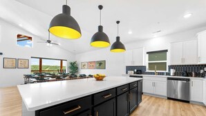 A modern kitchen with a large island, black cabinets, and pendant lighting. - Cozy Lakeview Lodge - Pools, Private Hot Tub & Sauna, Game Room (Branson)
