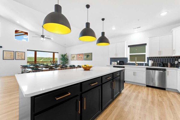 Een moderne keuken met een groot kookeiland, zwarte kastjes en hanglampen.