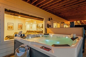 A hot tub with a control panel, a glass table with a wine glass, and a towel.