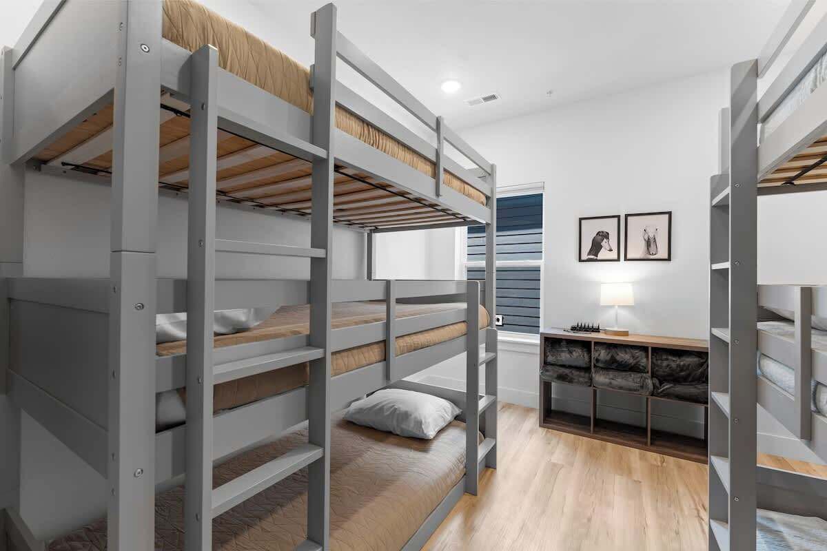 A bunk bed room with a desk and a lamp.