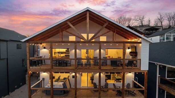 A multi-story building with a wooden balcony, a kitchen area on the upper floor, and a dining area on the lower floor. - Cozy Lakeview Lodge - Pools, Private Hot Tub & Sauna, Game Room (Branson)