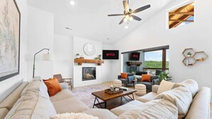 A modern living room with a large sofa, a coffee table, a fireplace, and a television. - Cozy Lakeview Lodge - Pools, Private Hot Tub & Sauna, Game Room (Branson)
