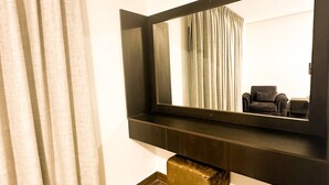 Ein Zimmer mit einem großen Spiegel, Holzboden, einer schwarzen Bank und einem Vorhang.