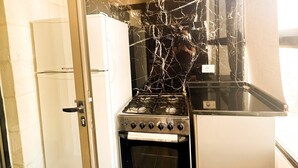 Eine kleine Küche mit Gasherd, Backofen und Kühlschrank.