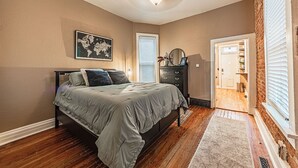 A bedroom with a bed, a dresser, a map on the wall, and a door leading to a bathroom. - Cozy, Historic Home in A++ Location!! (Denver)