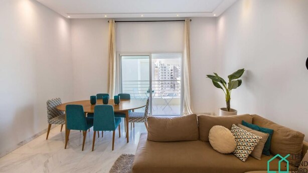 A modern living room with a sofa, a dining table with chairs, a large window with curtains, and a potted plant.