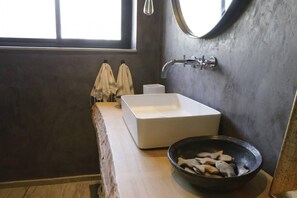 A bathroom with a large rectangular sink, a round mirror, and a bowl of fish on the counter. - The Central Point of La Marsa (La Marsa)
