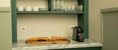 Une cuisine dotée d’un plan de travail en marbre, d’une machine à café et d’une planche à découper en bois avec un couteau.