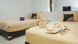 A hotel room with two beds, beige bedding, a large mirror, a TV, and a sign indicating a no-smoking area. - Singgahsini Rock Gubeng (Surabaya)