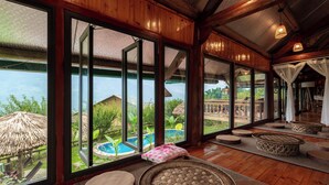 Una habitación amplia con ventanas grandes, suelo de madera y vistas a una piscina y jardín.